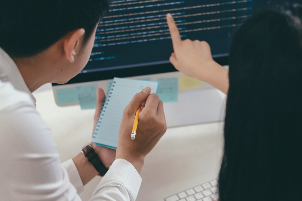 Two colleagues reviewing data on screen, representative of the manual cross-referencing workflows Agentic Launchpad automates